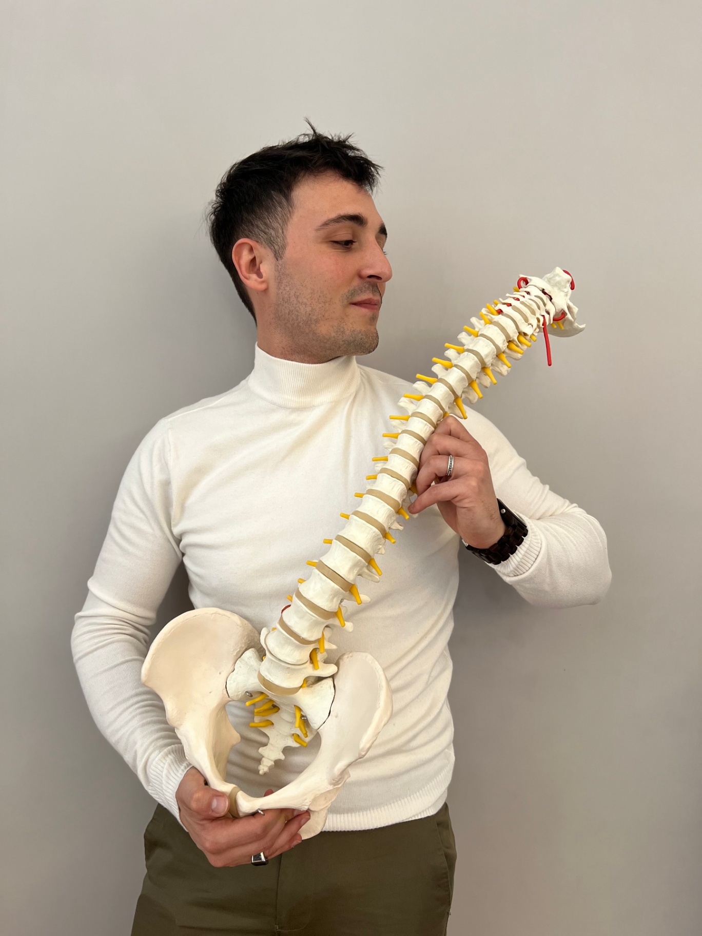 Simone Loi osteopata a Roma con modello anatomico della colonna vertebrale